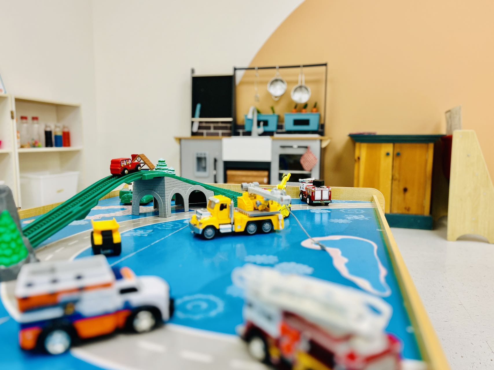 A toddler play table with a road and toy vehicles